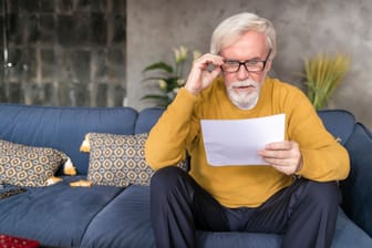 Älterer Mann liest ein Dokument (Symbolbild): Viele Eheleute regeln ihren Nachlass mit dem Berliner Testament.