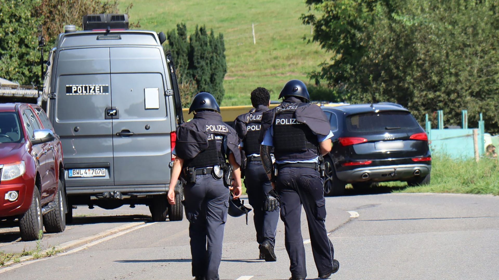 Polizisten in Schutzwesten gehen in Heiligkreuzsteinach über die Straße.