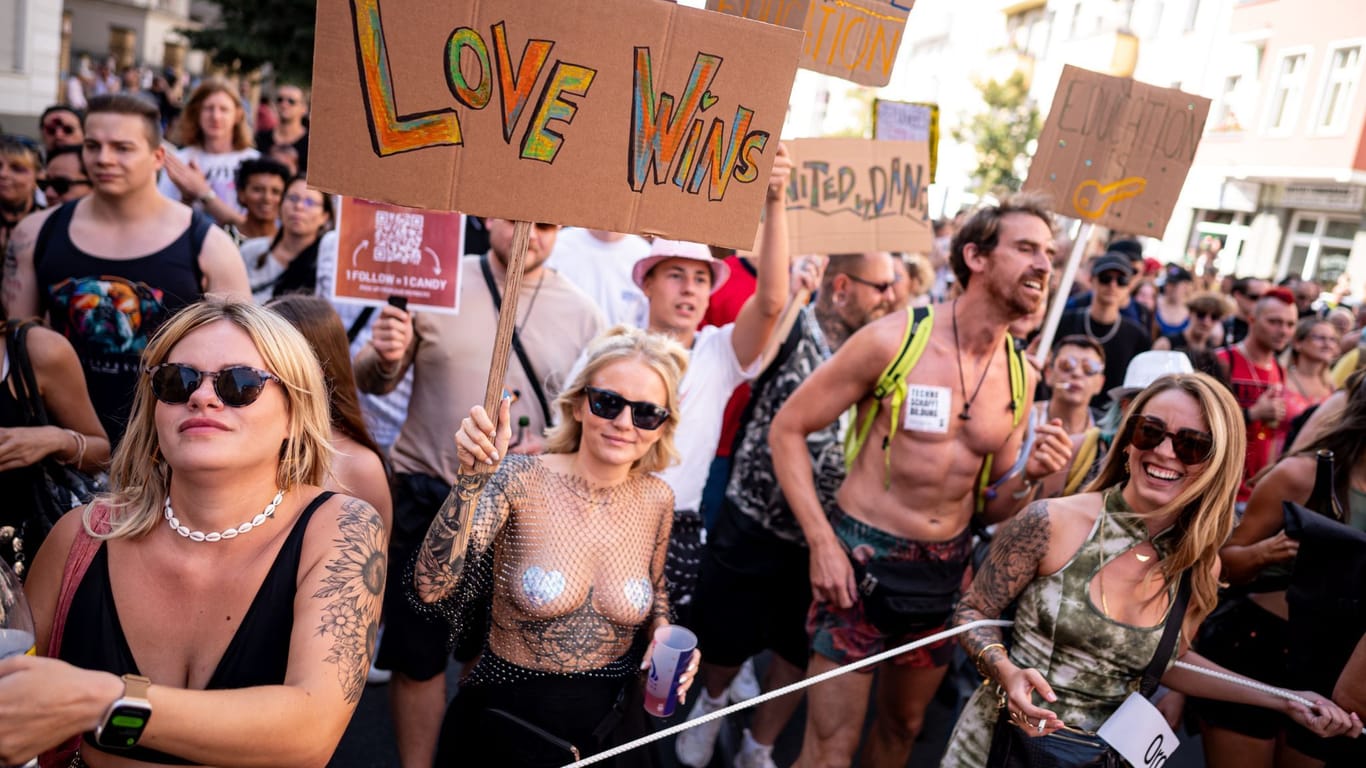 31.08.2024, Berlin: Menschen nehmen an der Technoparade «Zug der Liebe» - Demonstration für Toleranz, Vielfalt und Miteinander mit einem Schild mit der Aufschrift «love wins» teil. Foto: Fabian Sommer/dpa