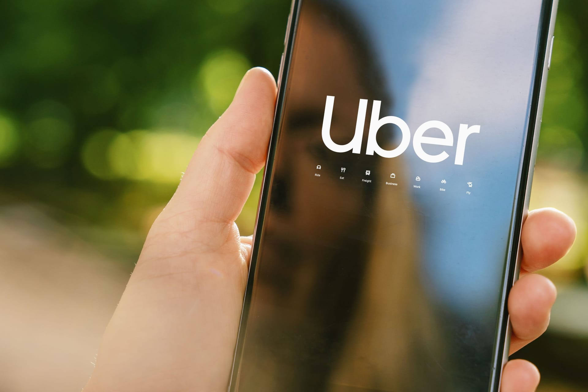 Uber driver holding smartphone in car. Uber is an American company offering different transportation services online