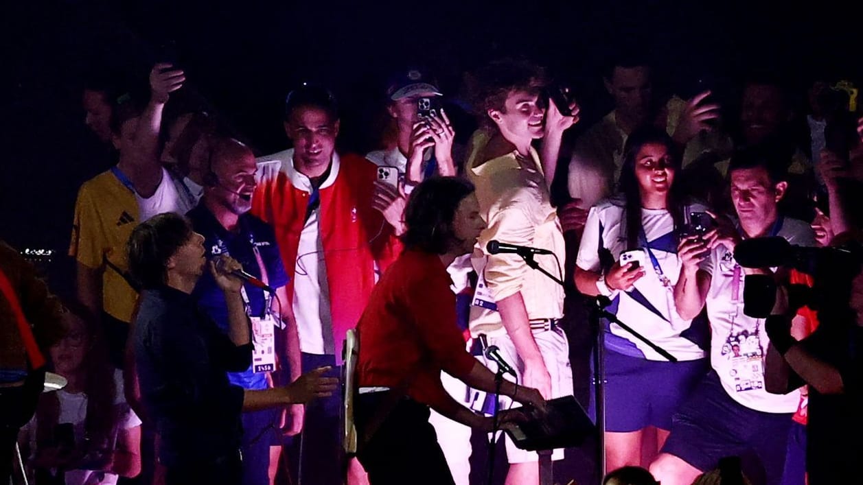 Athleten stehen neben der Band Phoenix auf der Bühne beim Abschluss der Olympischen Spiele.