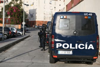 Spanische Polizisten stehen bei einem Einsatzfahrzeug.