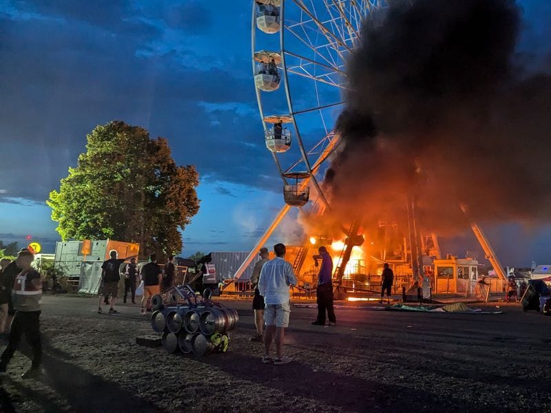 Festivalbesucher vor einem brennenden Riesenrad in Sachsen.