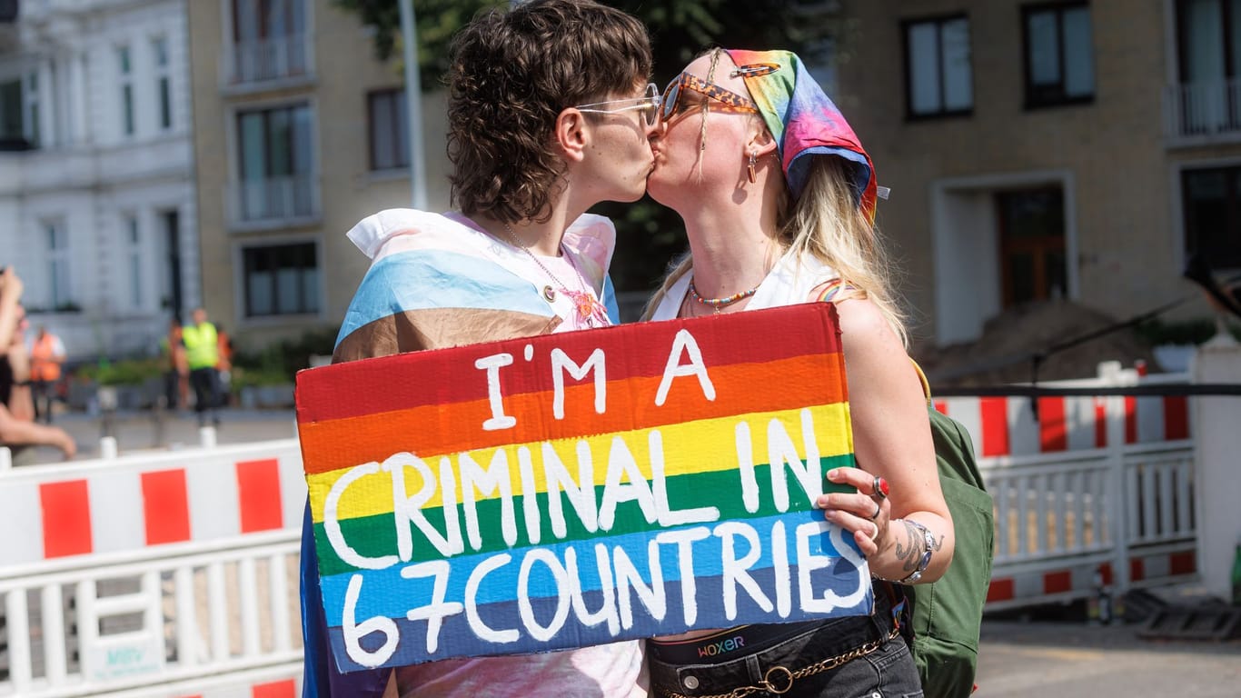 Zwei Frauen halten auf der Demonstration zum Christopher Street Day (CSD) ein Schild mit der Aufschrift "I am a criminal in 67 countries."