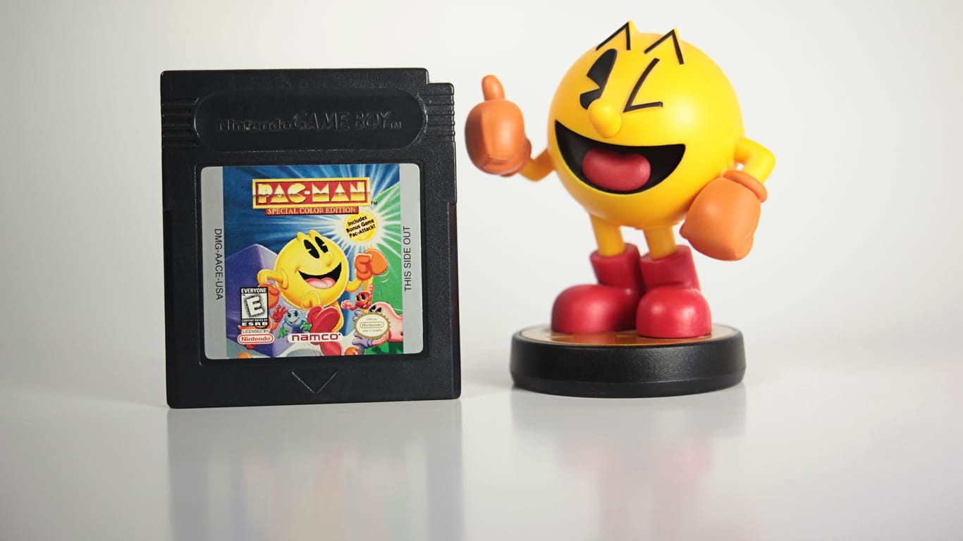 Eine Pac-Man-Figur steht neben einem Pac-Man-Videospiel für den Gameboy.