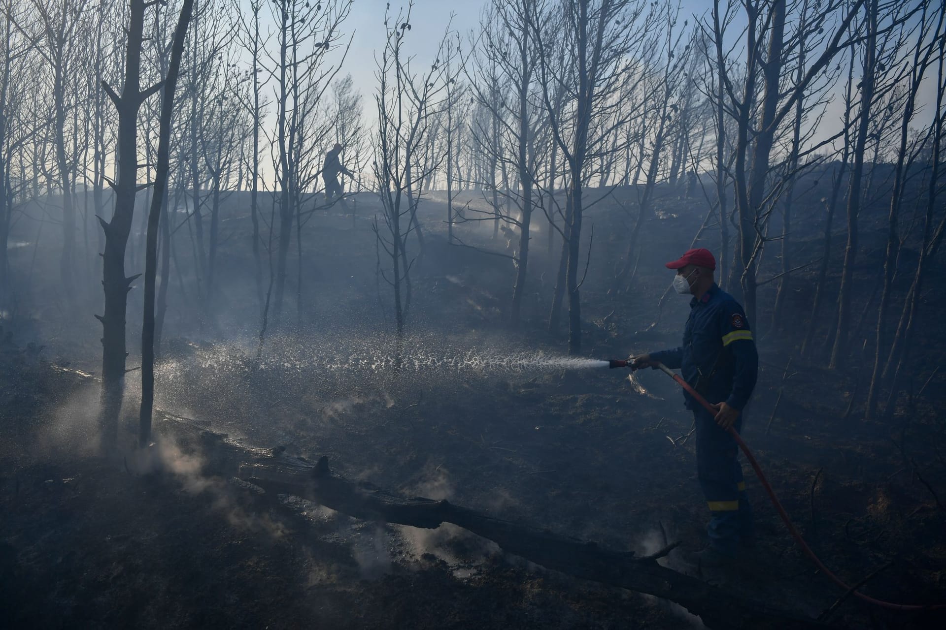 Feuerwehrleute sind bei Löscharbeiten im Einsatz in der Nähe von Penteli, nordöstlich von Athen.