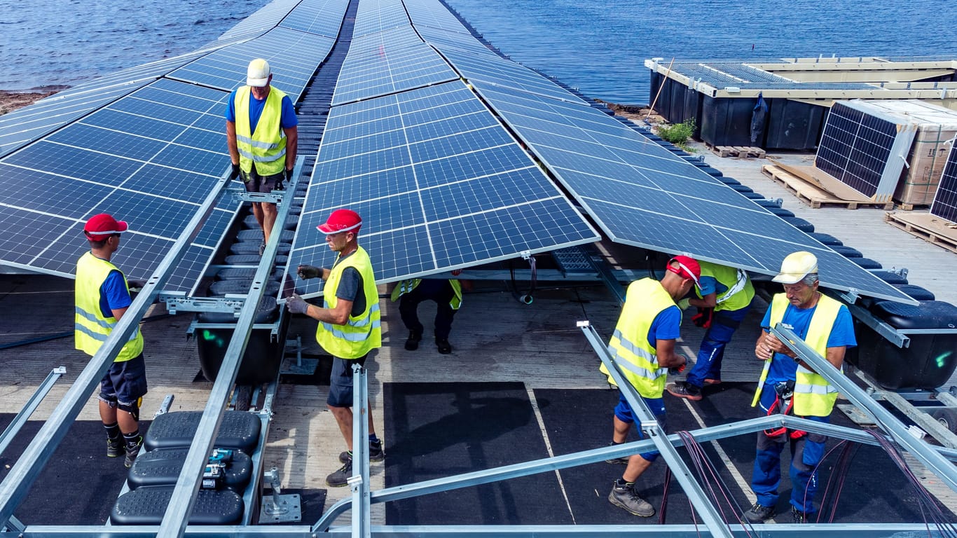 Arbeiter montieren Solarmodule für eine Photovoltaikanlage auf dem Cottbuser Ostsee im brandenburgischen Neuendorf: Projekte wie dieses müssen erst einmal finanziert werden.