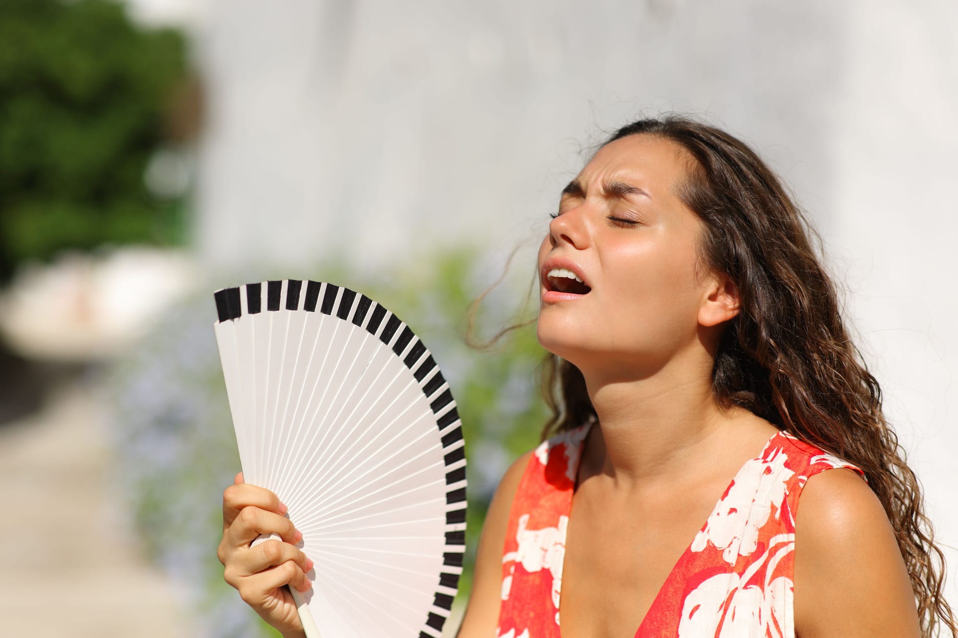 Eine Frau mit einem Fächer (Archivbild): In Sachsen steigen die Temperaturen an.