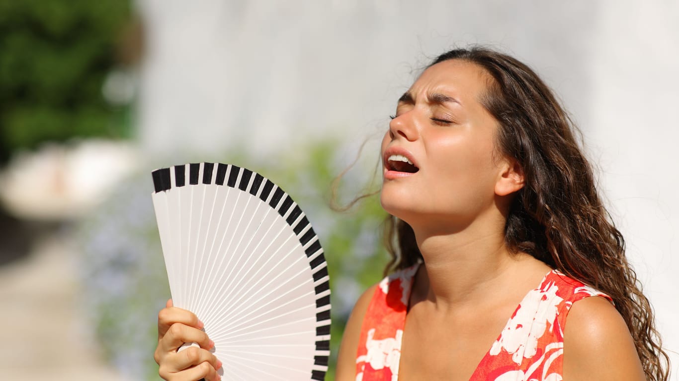 Eine Frau mit einem Fächer (Archivbild): In Sachsen steigen die Temperaturen an.