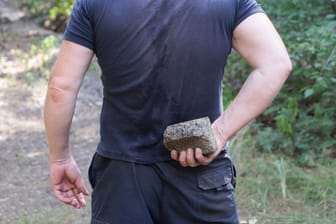 Ein Mann hält einen Stein in der Hand (Symbolbild): In Niederschöneweide wurde eine Frau mit einem Pflasterstein verletzt.