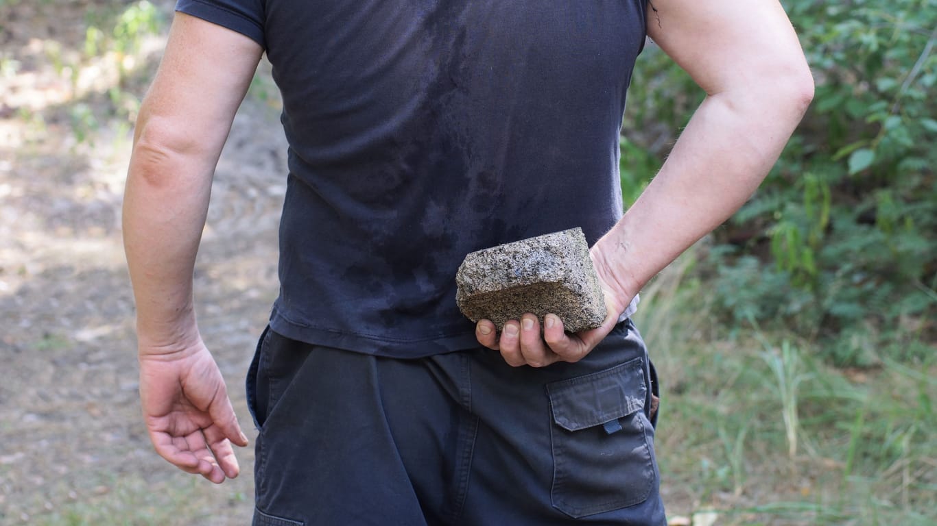 Ein Mann hält einen Stein in der Hand (Symbolbild): In Niederschöneweide wurde eine Frau mit einem Pflasterstein verletzt.