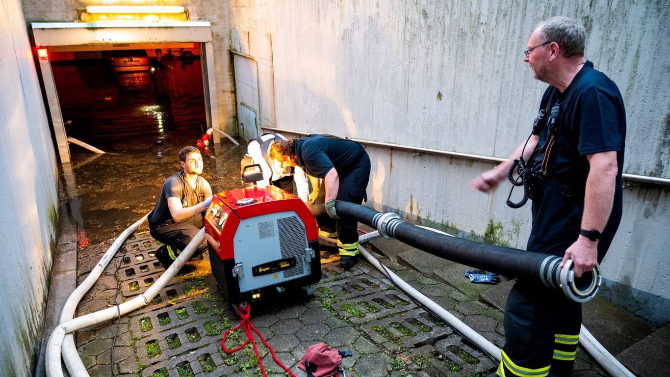 Feuerwehrleute pumpen im Stadtteil Billstedt Wasser aus einer durch Starkregen überfluteten Tiefgarage.