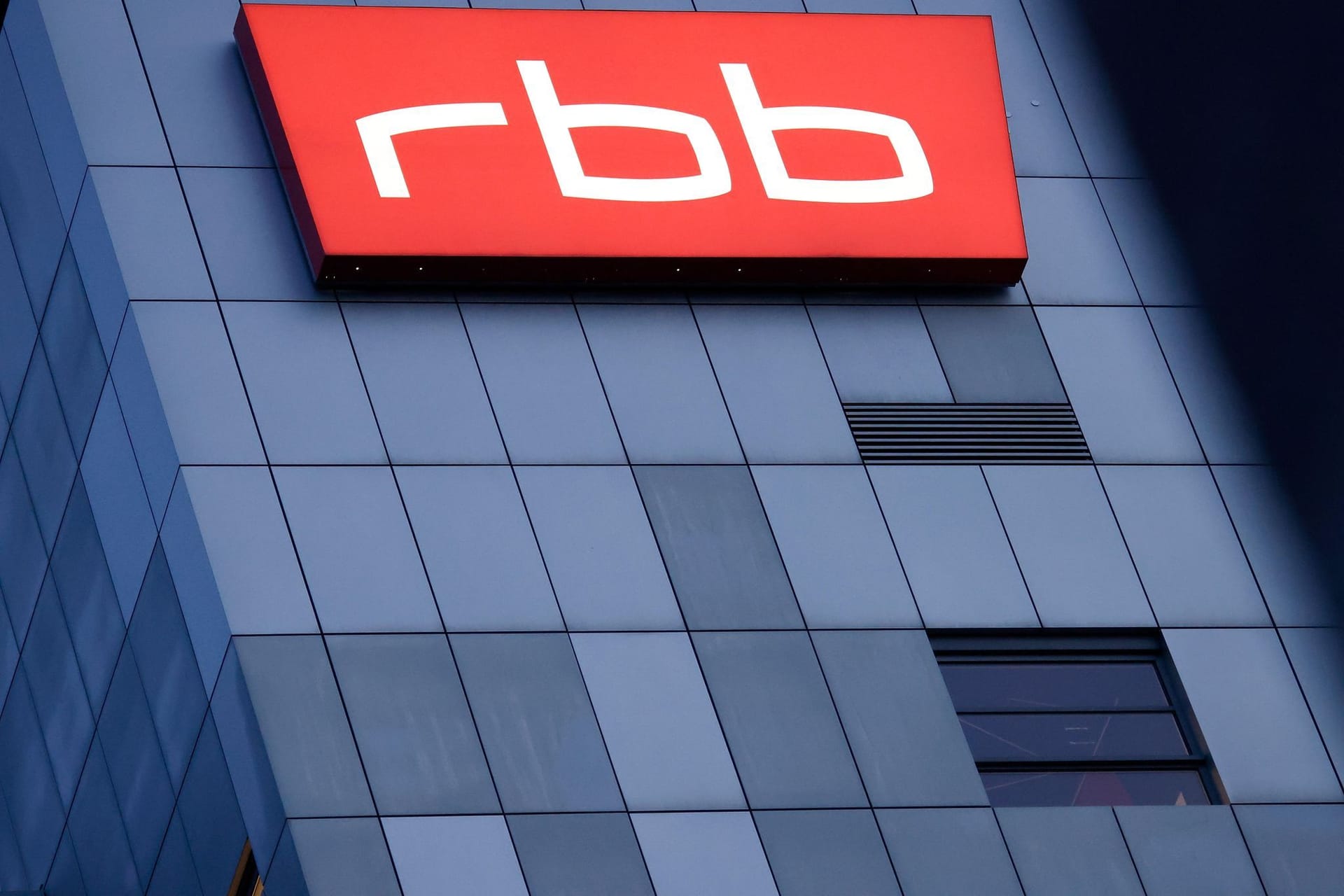 ARCHIV - 15.08.2022, Berlin: Das beleuchtete Logo des Senders Rundfunk Berlin-Brandenburg (RBB) ist an der Fassade am Sitz des Senders an der Masurenallee angebracht