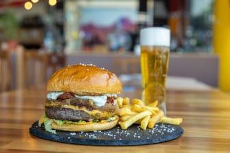 Closeup shot of a hamburger with cutlet and cheese, fries and beer