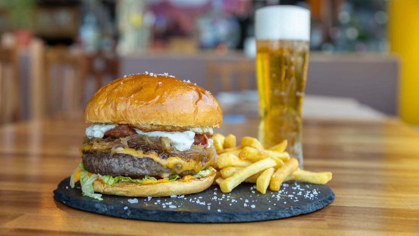 Closeup shot of a hamburger with cutlet and cheese, fries and beer