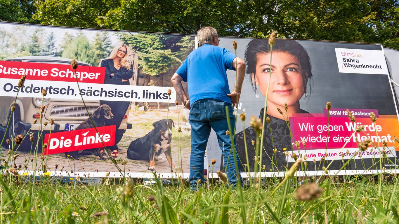 Ein Mann blickt auf ein Wahlplakat der BSW Sachsen.