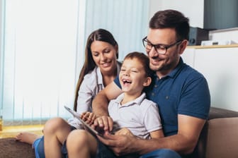 Eltern mit ihrem Sohn schauen auf ein Tablet