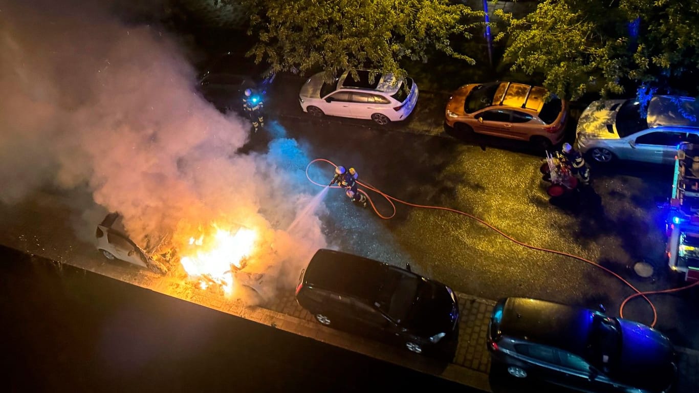 Zwei brennende Pkw werden von der Feuerwehr München gelöscht.