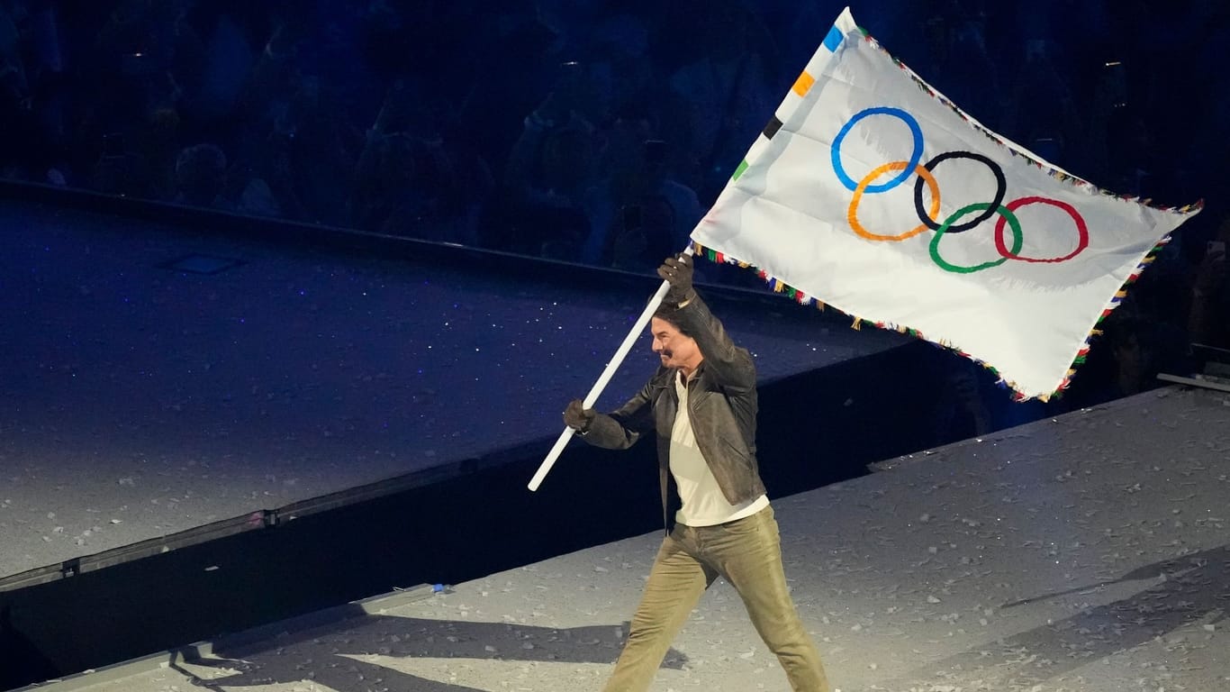 Tom Cruise trägt die olympische Fahne.