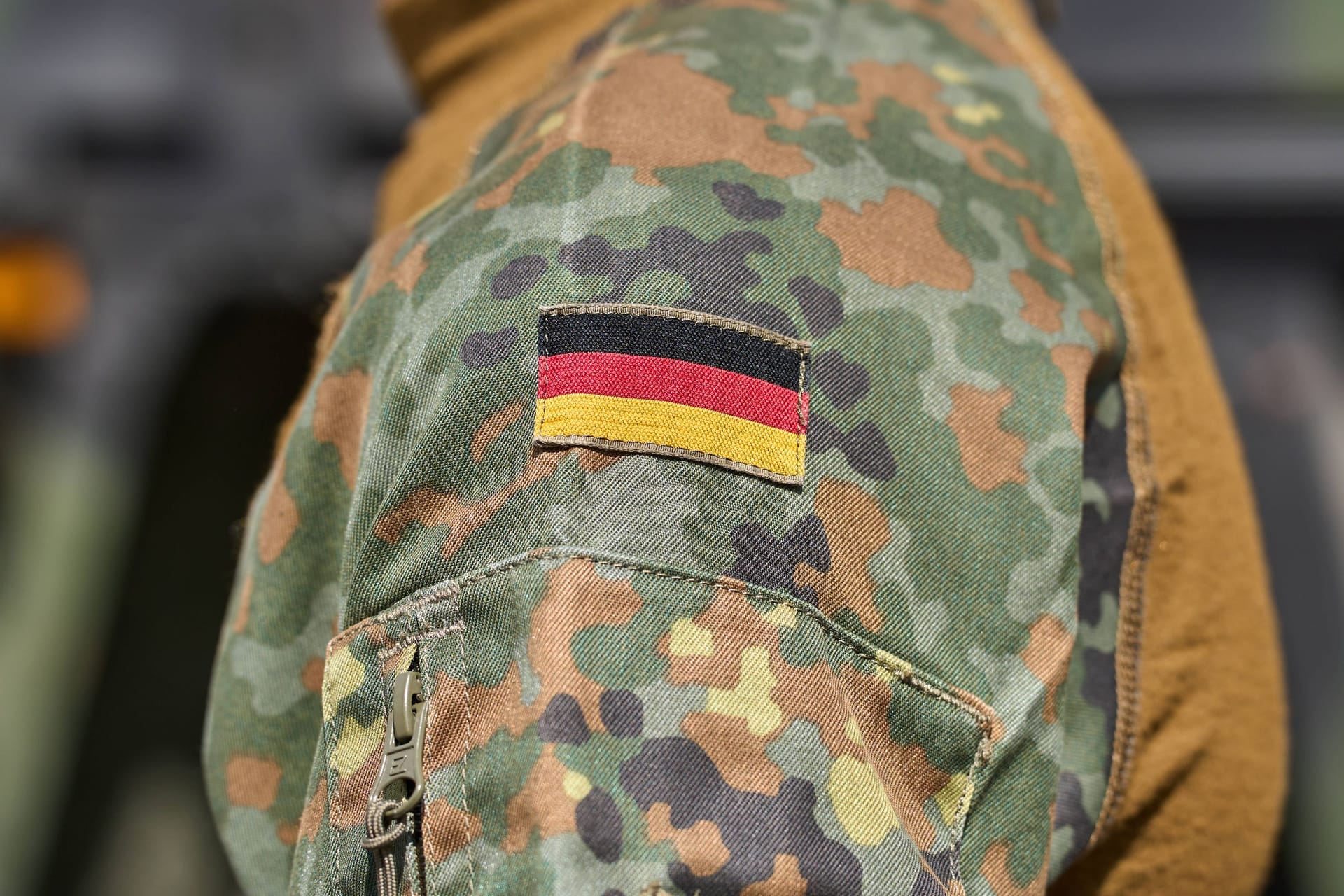 Soldat der deutschen Bundeswehr in Uniform vor einem Militärfahrzeug. Deutschland Flagge auf der Schulter der Bundeswehruniform