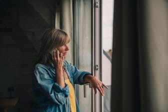 Eine Frau telefoniert am Fenster