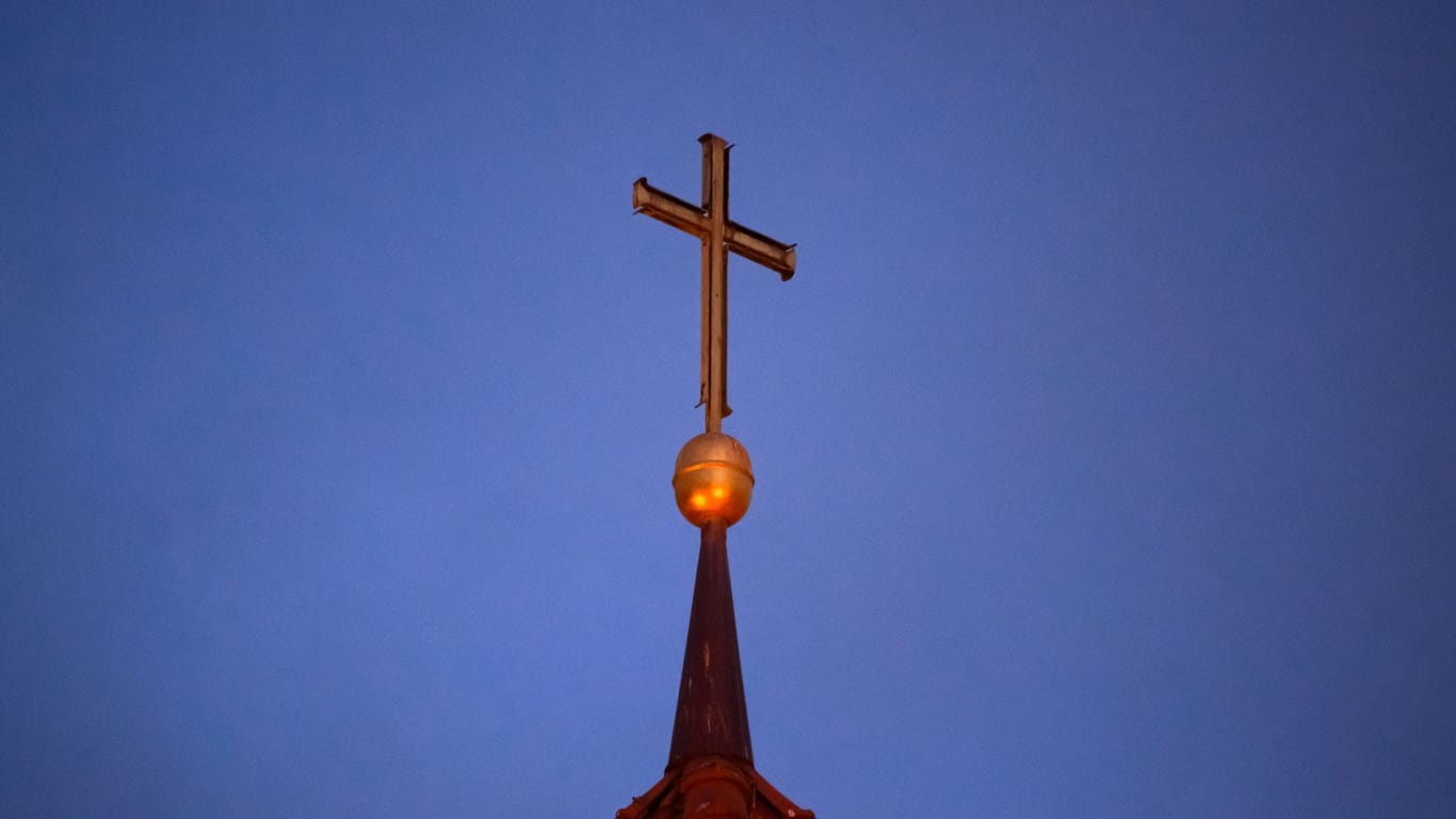 Ein Kreuz steht auf der Kirchturmspitze einer evangelischen Kirche in der Region Hannover.