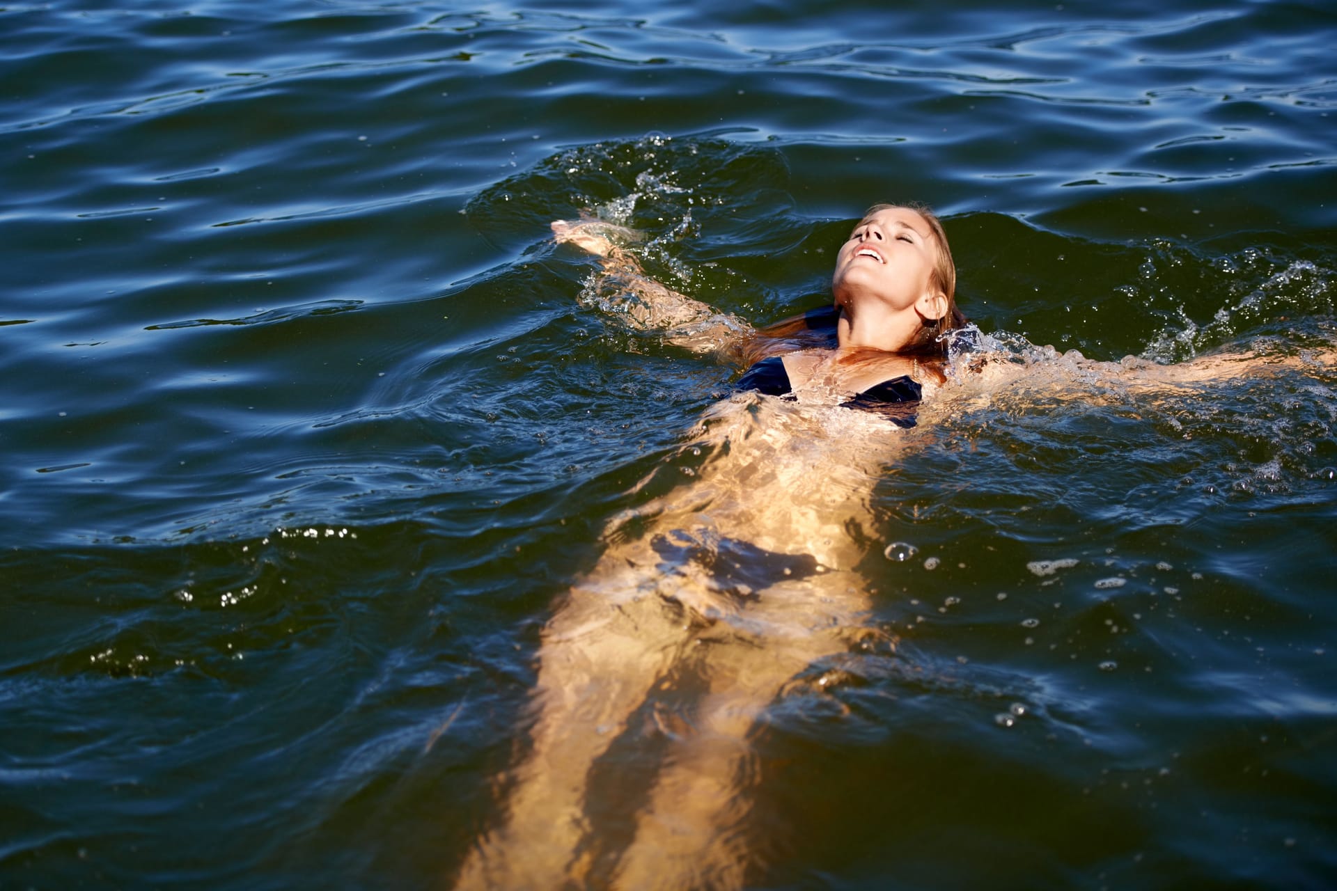 Bikini, woman and floating in water at lake to relax in summer, holiday and swimming on vacation. Calm, peace and person in swimwear, fashion or body in waves of ocean or sea with freedom in nature