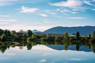 The village and church of Koenigsdorf in Bavaria with the Bibi Lake in the foreground and the mountains in the background