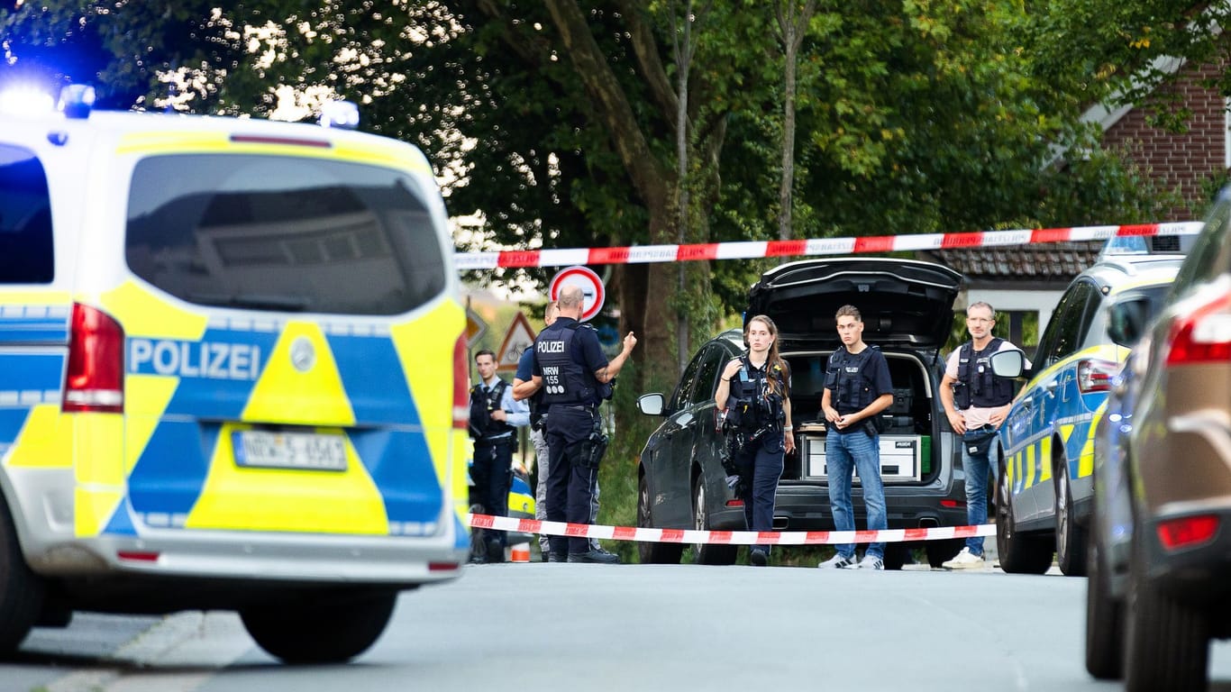 Recklinghausen: Einsatzkräfte der Polizei stehen an einem Tatort zwischen Fahrzeugen.