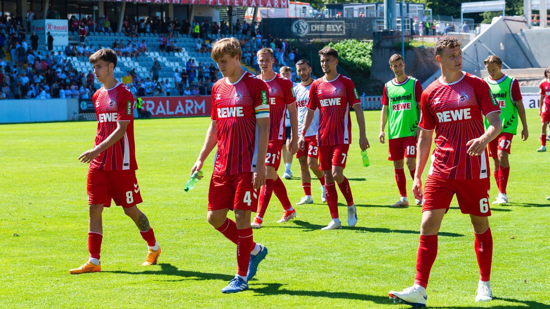 Die Kölner Denis Huseinbasic, Timo Hübers und Eric Martel gehen nach dem Spiel über den Platz.