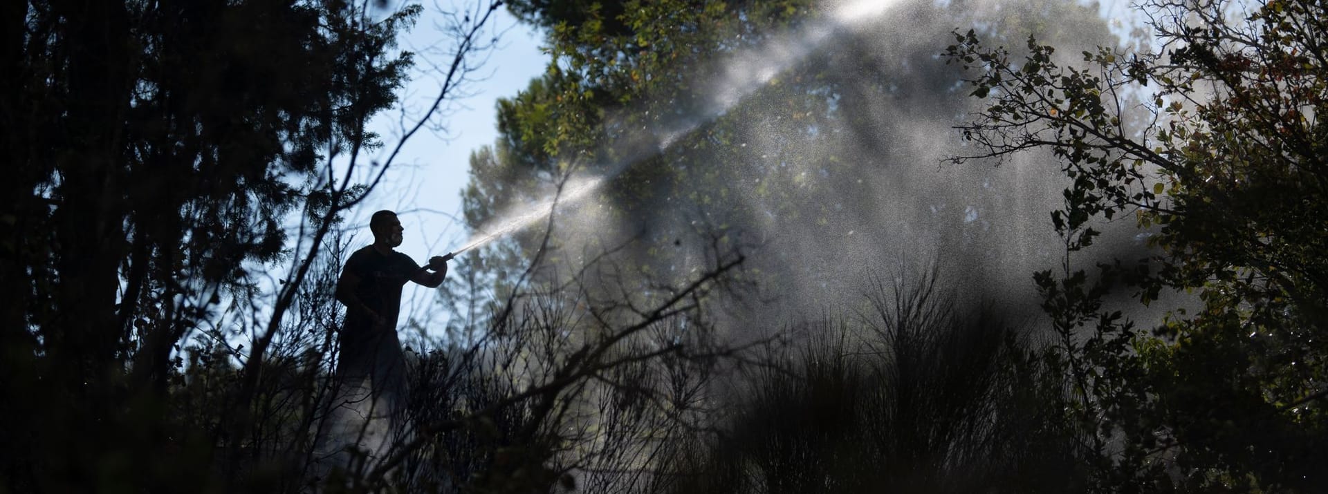 Ein Freiwilliger versprüht während eines Waldbrandes im Dorf Varnava Wasser mit einem Schlauch.