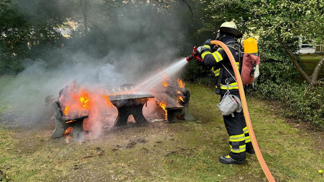 Einsatzkräfte löschen eine Sitzgruppe aus Holz an der Grundschule: Zuvor hatte sich starker Rauch entwickelt.