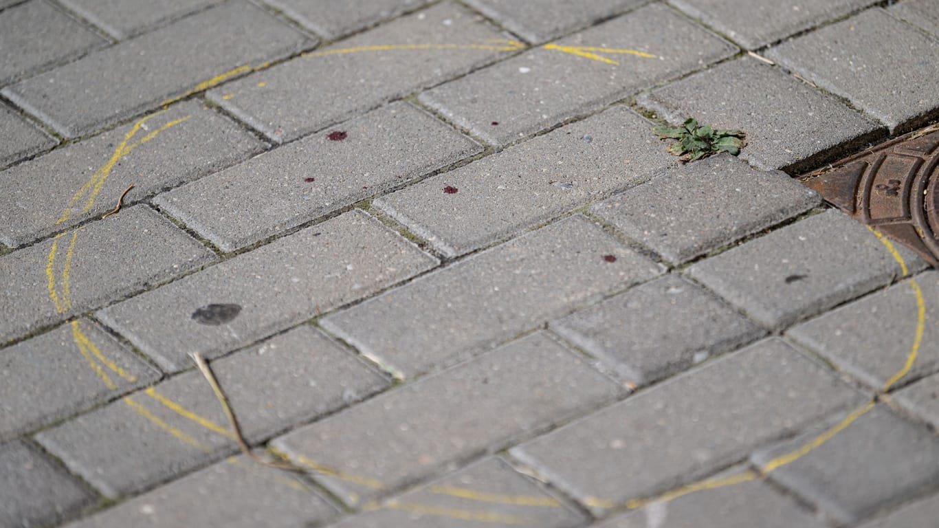 Mit einem gelben Kreis markierte Blutstropfen sind nach einem tödlichen Messerangriff auf dem Boden vor einem Hauseingang in Berlin-Friedrichsfelde zu sehen.