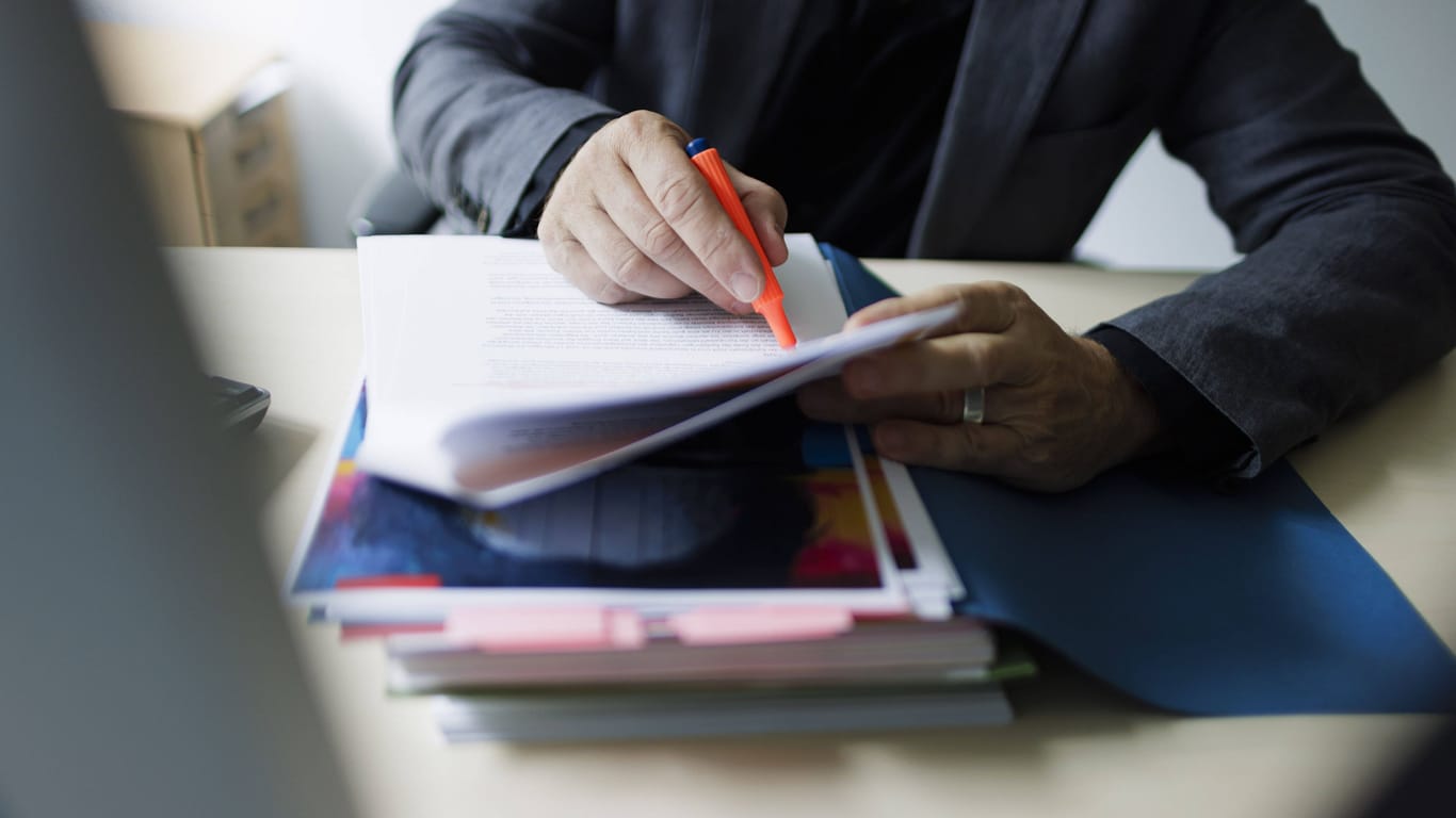 Mitarbeiter bearbeitet Akten (Symbolbild): Beim Finanzamt sammeln sich viele persönliche Informationen.