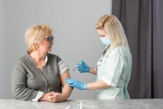 Senior vaccination concept. Elderly getting immune vaccine at arm for flu shot, pneumonia, and shingles in hospital by nurse. Doctor giving an injection to older people patient in clinic