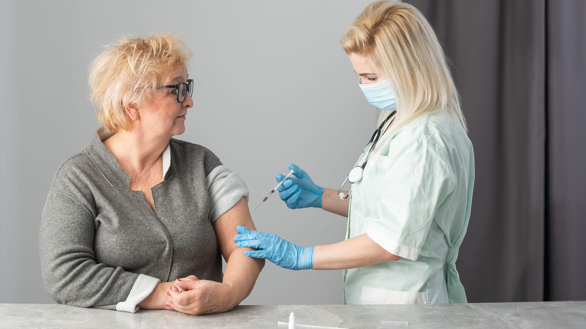 Senior vaccination concept. Elderly getting immune vaccine at arm for flu shot, pneumonia, and shingles in hospital by nurse. Doctor giving an injection to older people patient in clinic