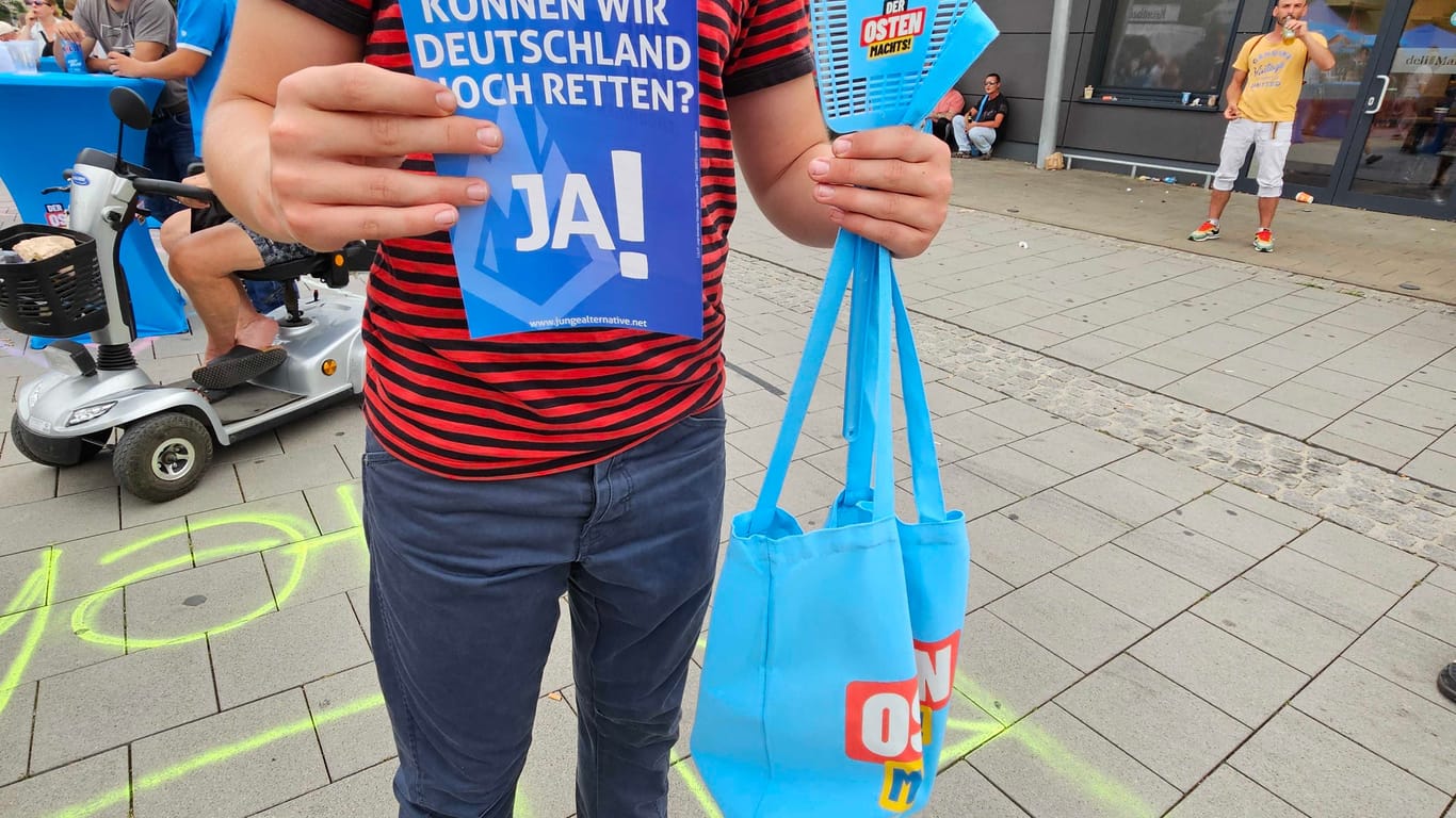 AfD-Fliegenklatsche und Tasche mit Print "Der Osten macht's": Junger Besucher der AfD-Veranstaltung mit Werbematerial.