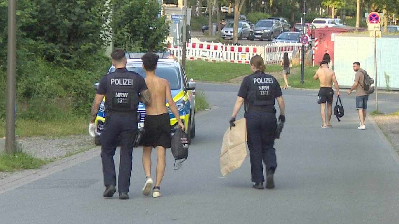 Einsatz am Freibad: Die Polizei bringt einen jungen Mann zu einem Streifenwagen.