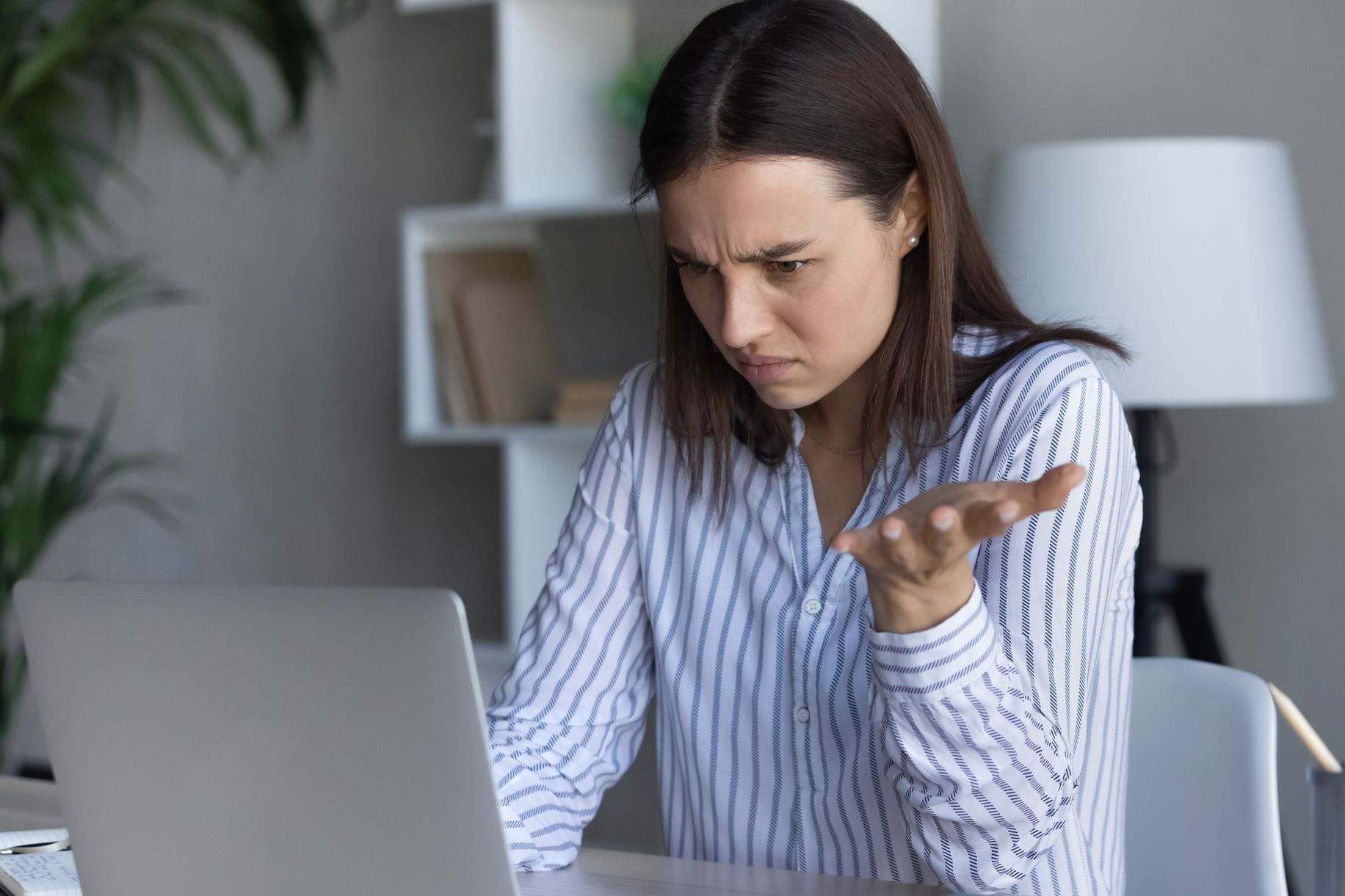 Frau am Laptop ärgert sich über eine Nachricht