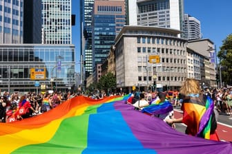 Menschen feiern mit einer großen Regenbogenfahne beim Christopher Street Day (CSD) Frankfurt: Das diesjährige Motto lautet "Wir sind extrem liebevoll".