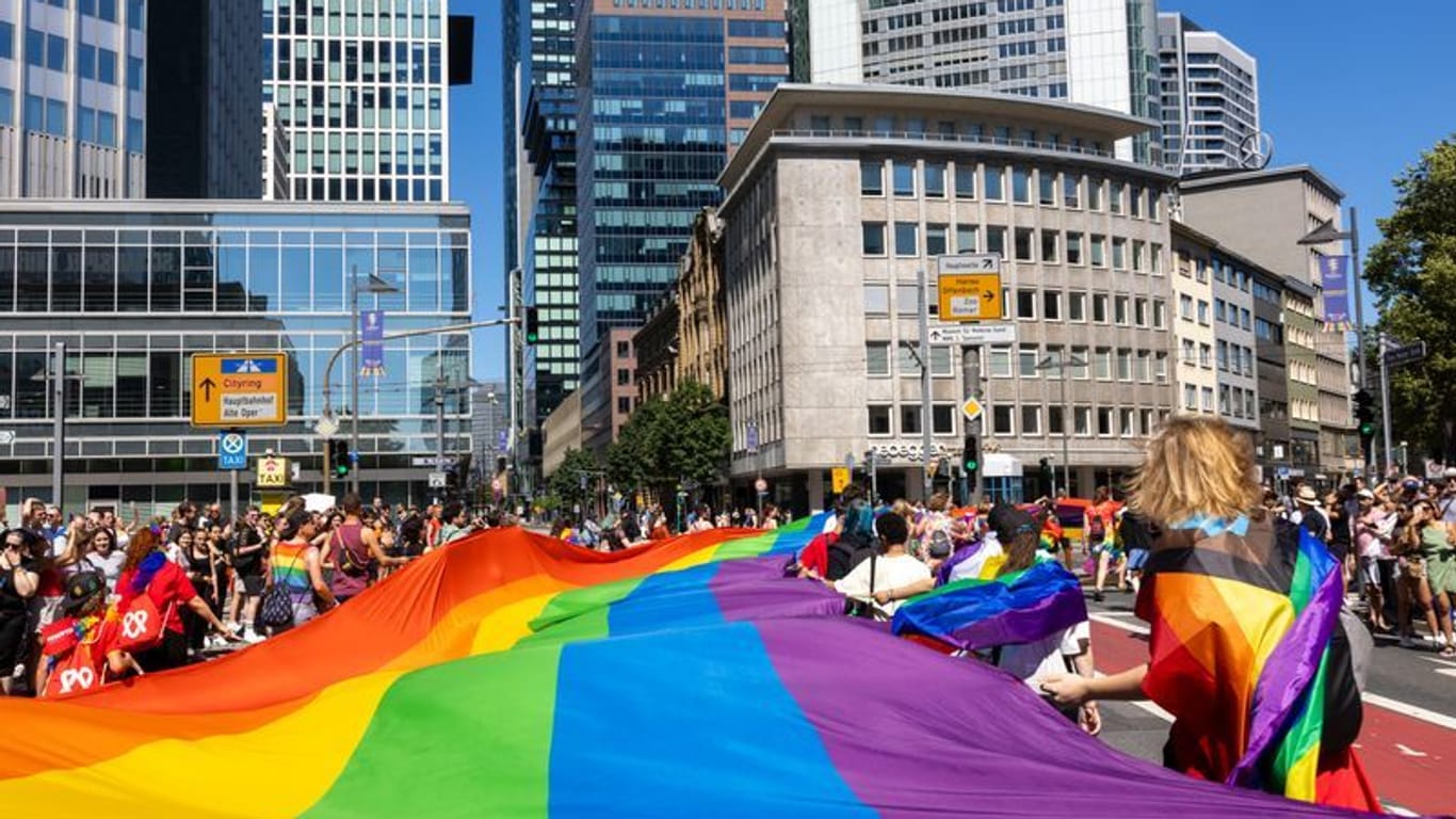 Menschen feiern mit einer großen Regenbogenfahne beim Christopher Street Day (CSD) Frankfurt: Das diesjährige Motto lautet "Wir sind extrem liebevoll".