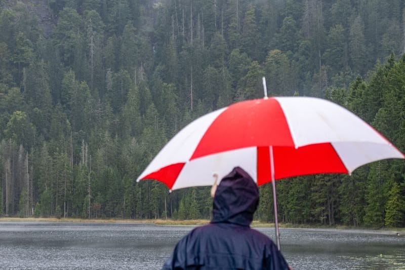 Ein Wanderer steht mit einem Regenschirm am Ufer des Arbersees: Am Wochenende hat der Wetterdienst vor Starkregen gewarnt.