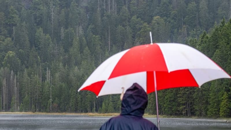 Ein Wanderer steht mit einem Regenschirm am Ufer des Arbersees: Am Wochenende hat der Wetterdienst vor Starkregen gewarnt.