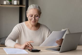 Ältere Frau berechnet ihre Finanzen: Wird die Lebensversicherung ausgezahlt, stehen Ihnen viele Wege offen.