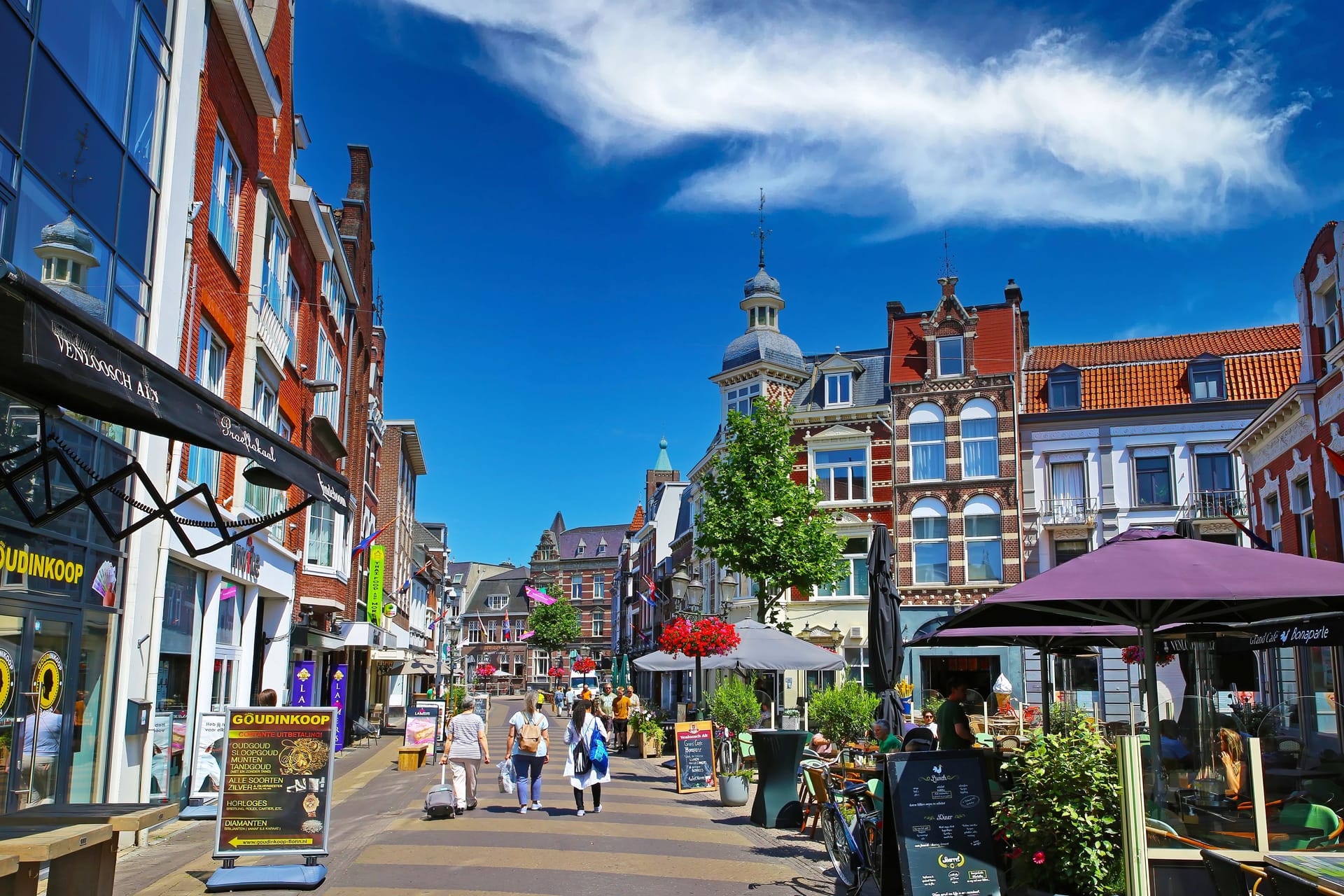 Venlo, Netherlands - July 9. 2022: Beautiful shopping street, typical colorful old dutch houses, exterior cafes and restaurants, blue summer sky