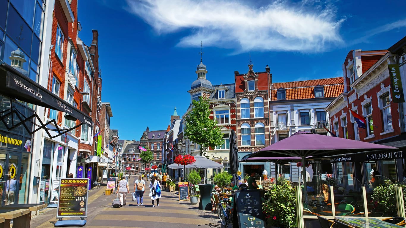 Venlo, Netherlands - July 9. 2022: Beautiful shopping street, typical colorful old dutch houses, exterior cafes and restaurants, blue summer sky