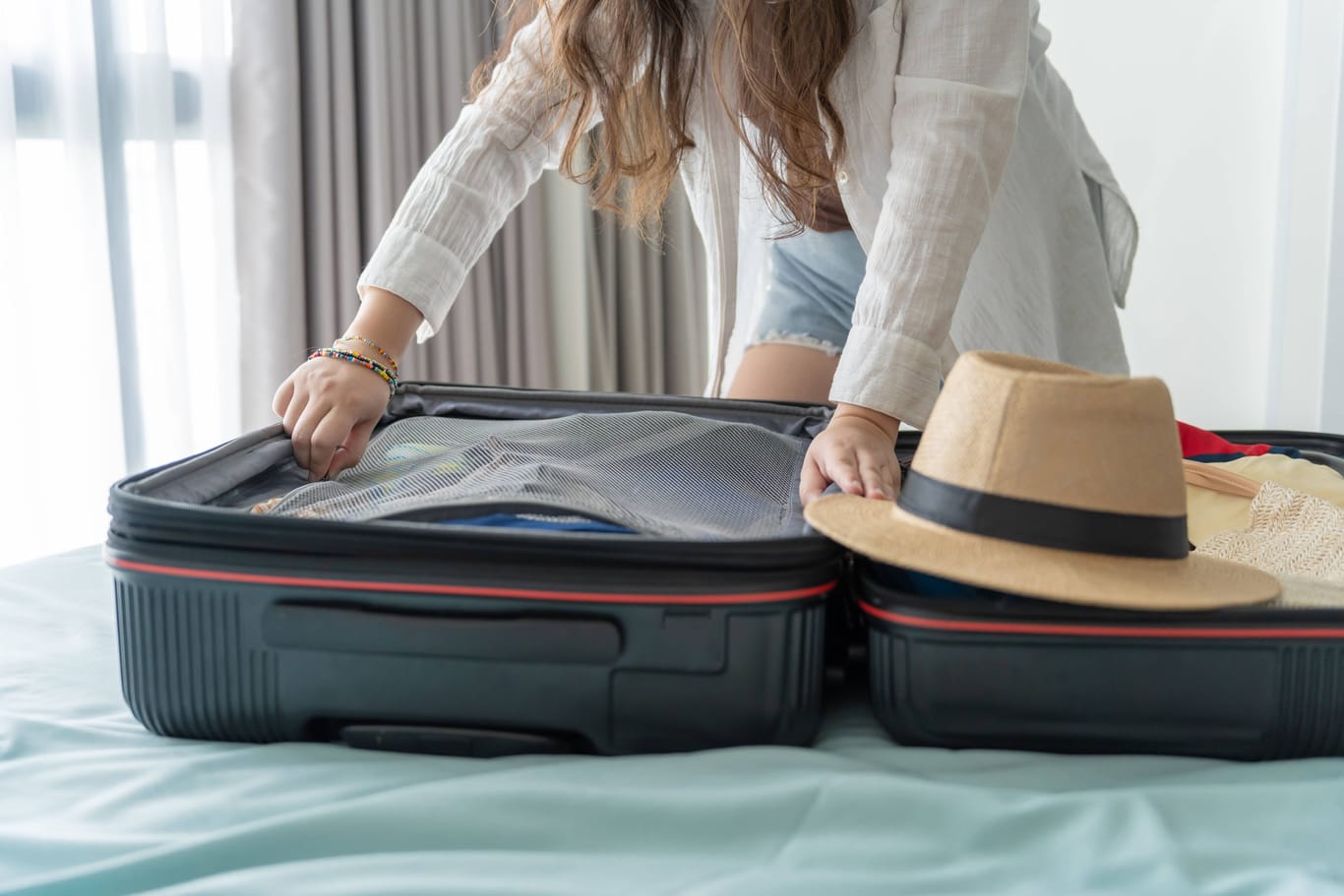 Eine Frau packt ihren Koffer auf einem Hotelbett aus (Symbolbild): In anderen Städten gibt es die Übernachtungssteuer bereits.