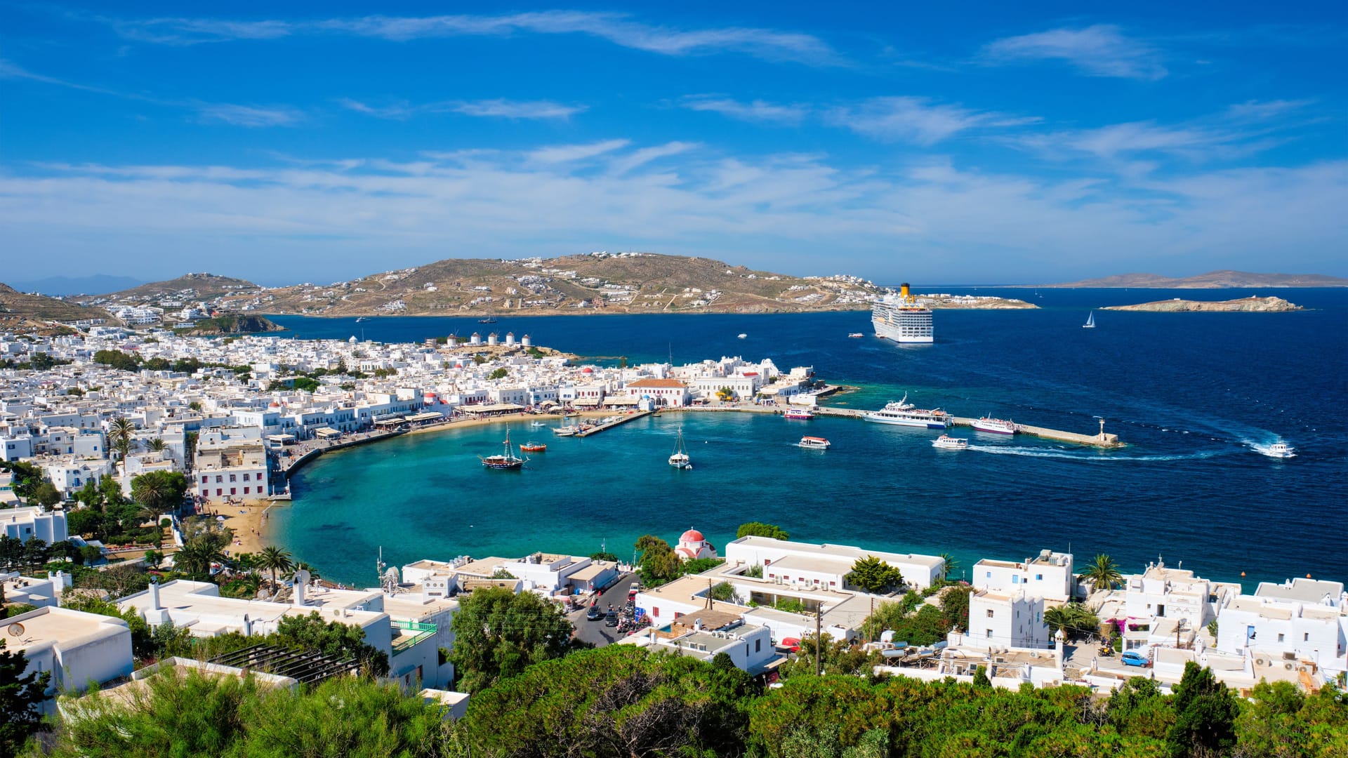 Der Hafen von Mykonos: Im Hintergrund liegt ein Kreuzfahrtschiff. Die großen Passagierschiffe besuchen die Insel in der Hauptsaison im Stundentakt.