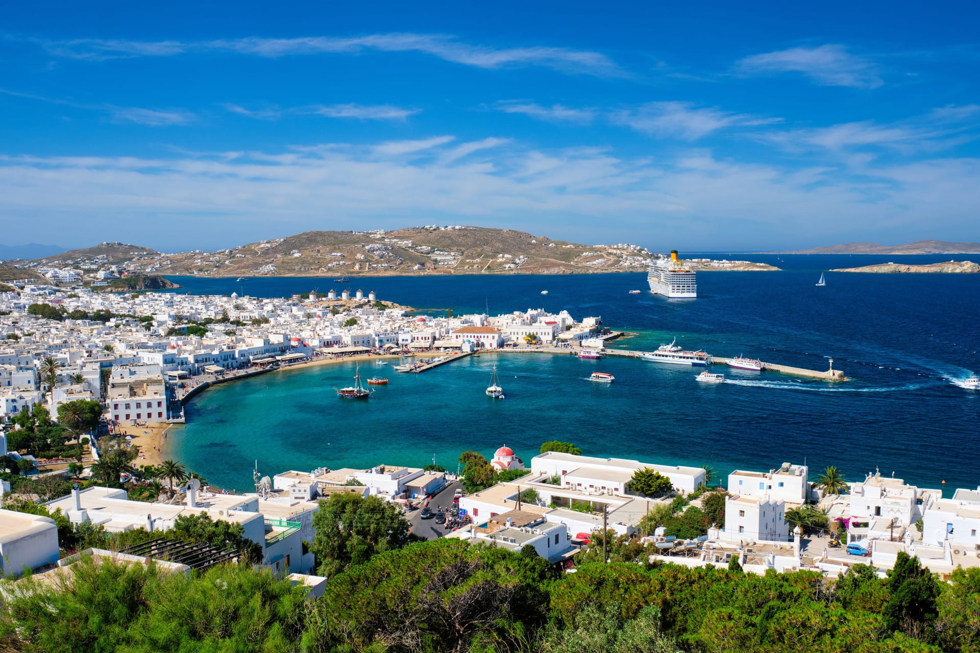 Der Hafen von Mykonos: Im Hintergrund liegt ein Kreuzfahrtschiff. Die großen Passagierschiffe besuchen die Insel in der Hauptsaison im Stundentakt.