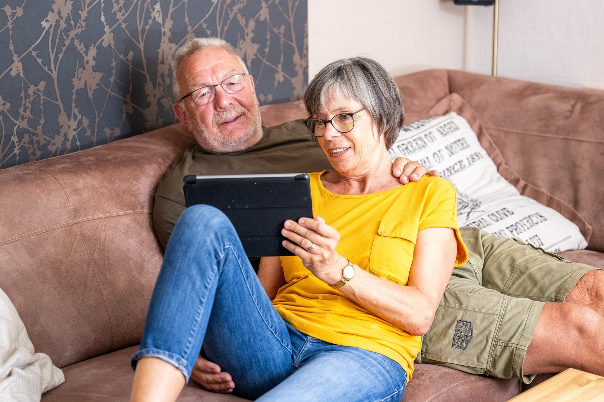 Ein Paar sitzt schaut auf ein Tablet Ein Paar sitzt schaut auf ein Tablet